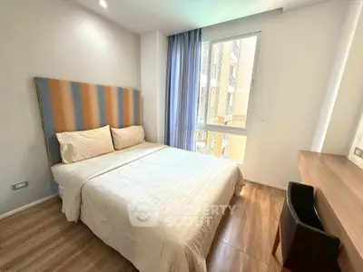 Modern bedroom with wooden flooring and large window for natural light.