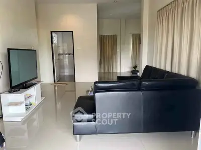 Modern living room with sleek black leather sofa and large TV, perfect for relaxation.