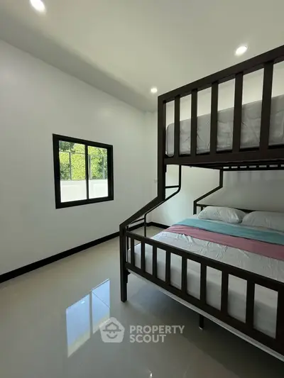 Modern bedroom with bunk beds and large window offering natural light.