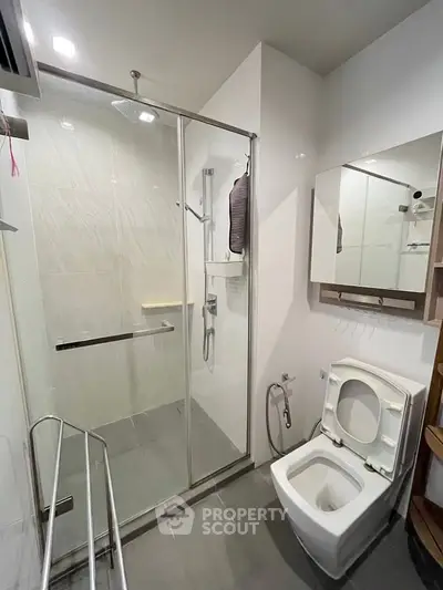 Modern bathroom with glass shower and sleek fixtures in contemporary home.