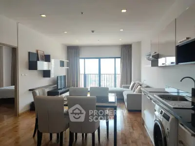 Modern open-plan living room with kitchen, featuring sleek furniture and natural light.