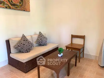 Cozy living room with wicker sofa, wooden chair, and coffee table in a stylish interior.