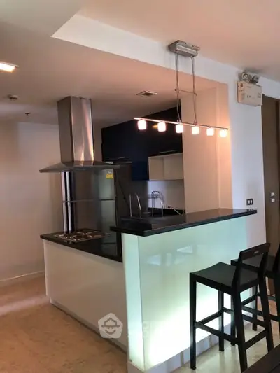 Modern kitchen with sleek bar counter and stylish lighting in contemporary apartment.