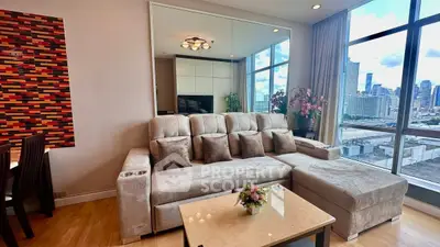 Spacious living room with city view, modern sofa, and elegant decor in high-rise apartment.