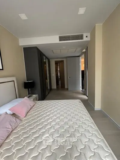Spacious bedroom with modern design and ample natural light, featuring a comfortable bed and stylish decor.