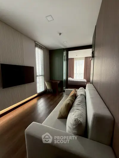 Modern living room with sleek design and natural light, featuring a cozy sofa and wall-mounted TV.
