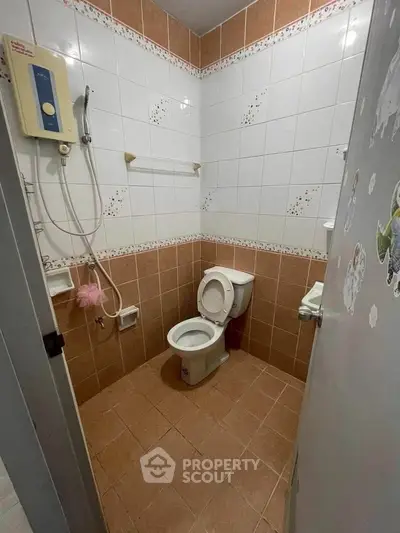 Compact bathroom with shower and toilet, tiled walls and floor, ideal for small spaces.