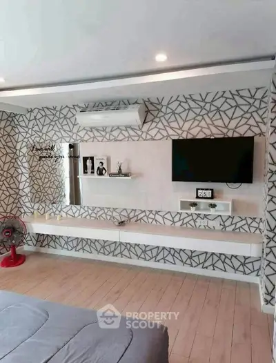 Modern bedroom with stylish decor and wall-mounted TV