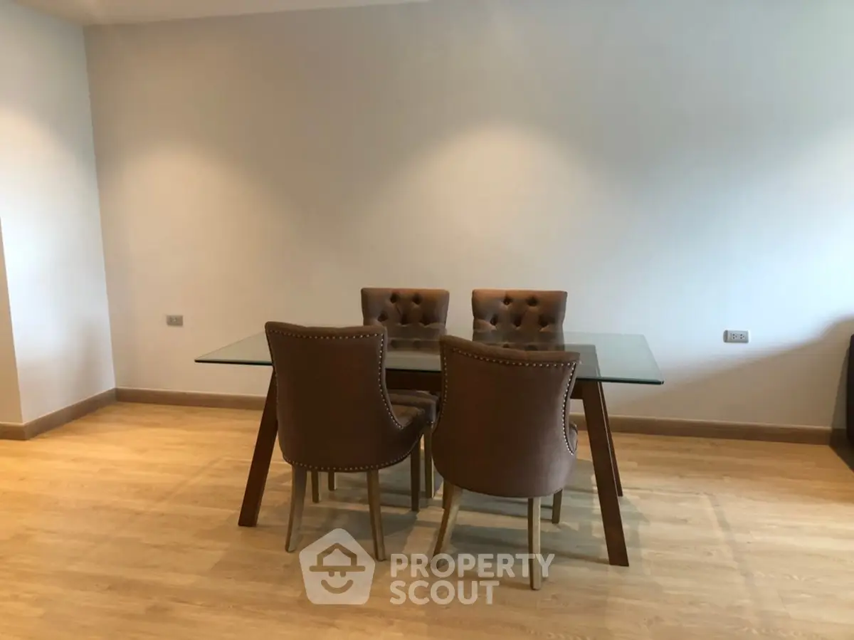Modern dining area with glass table and stylish chairs on wooden flooring.