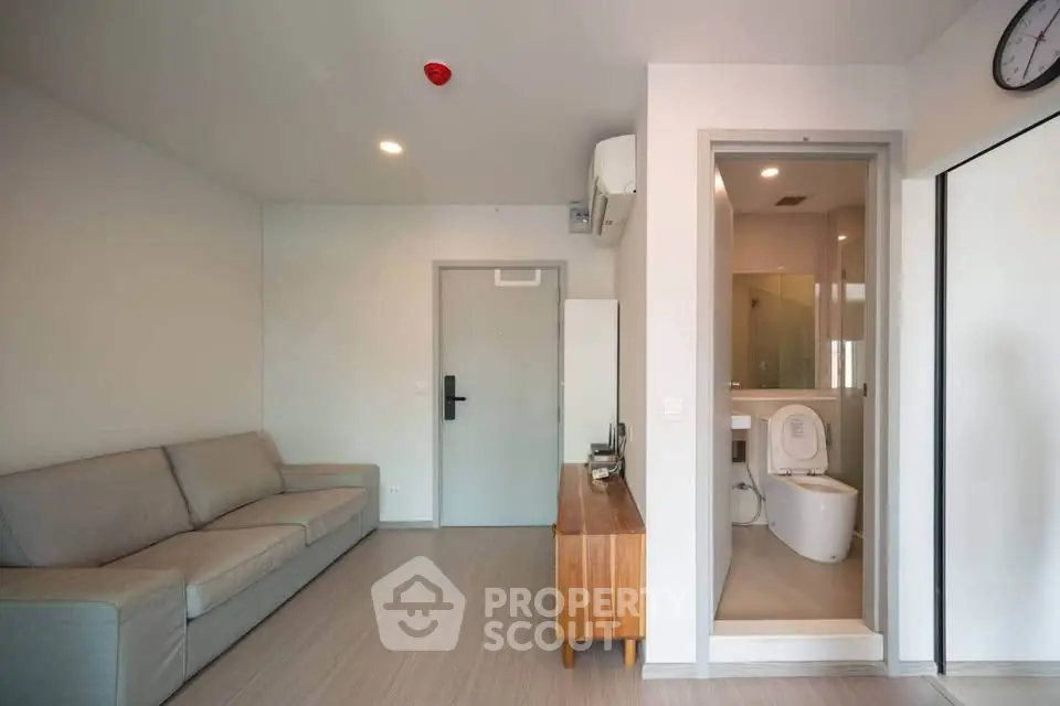 Modern apartment interior with cozy living room and adjacent bathroom, featuring sleek furniture and minimalist design.
