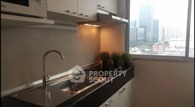 Modern kitchen with city view, featuring sleek cabinetry and stainless steel sink.