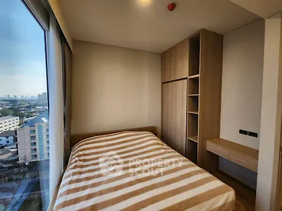 Cozy bedroom with city view, featuring a striped bedspread and built-in wooden wardrobe.