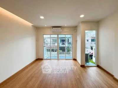 Spacious unfurnished room with wooden flooring and balcony access, ideal for customization.