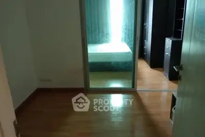 Spacious bedroom with wooden flooring and sliding glass door leading to a cozy bed area.