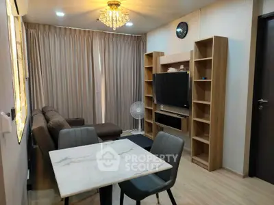 Modern living room with elegant chandelier and cozy seating area, featuring a stylish dining table and entertainment center.