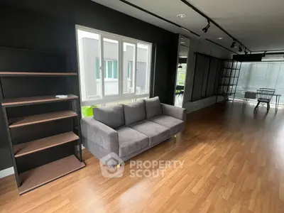 Spacious modern living room with sleek wooden flooring and stylish gray sofa, perfect for contemporary living.