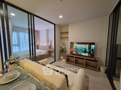 Modern living room with open layout and stylish decor, featuring a cozy bedroom view through glass partitions.