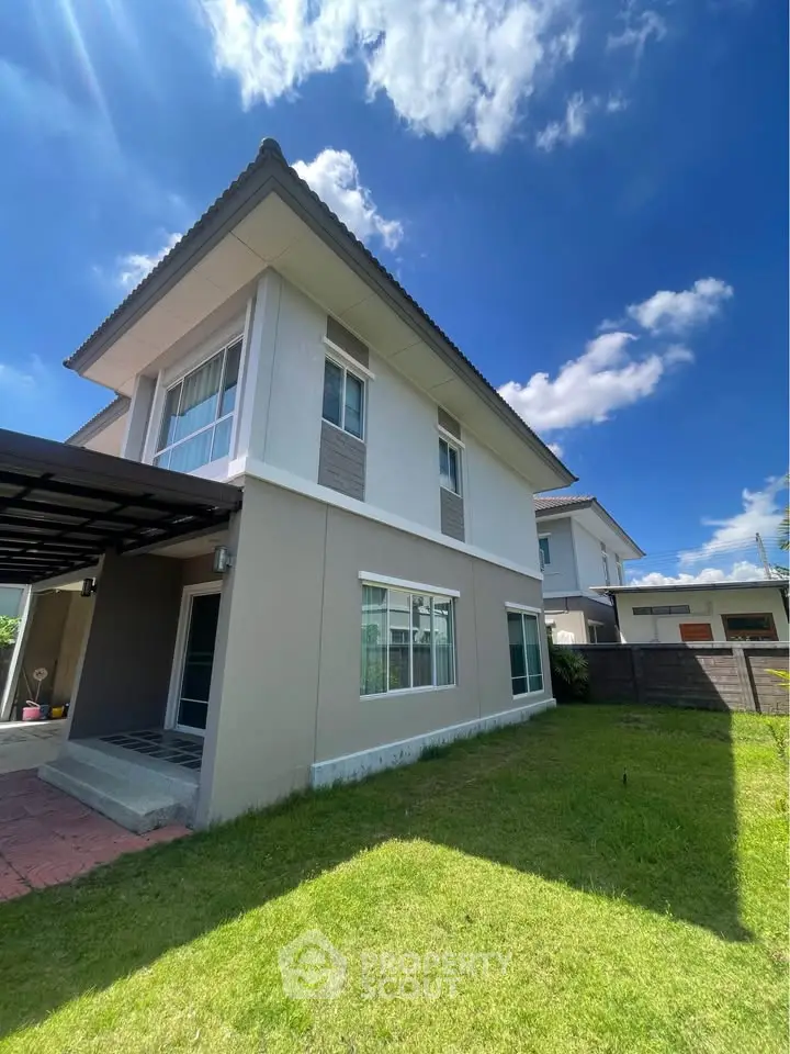 Charming two-story house with lush green lawn and clear blue sky, perfect for family living.