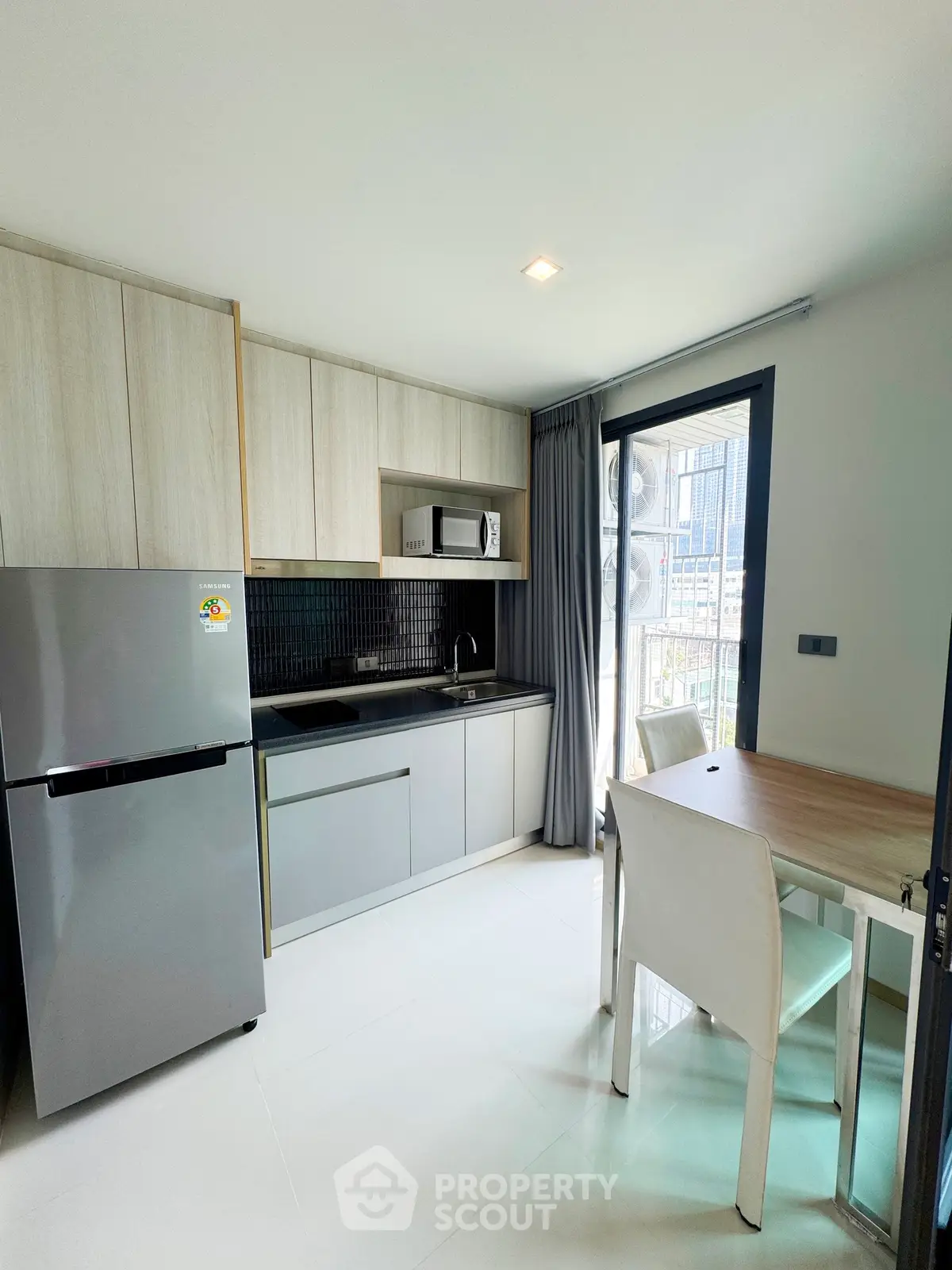 Modern kitchen with sleek cabinetry, stainless steel appliances, and dining area in bright apartment.