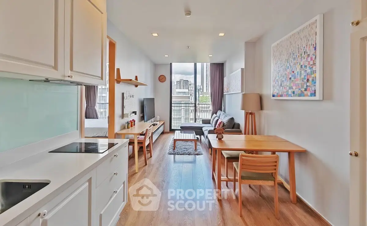 Modern open-plan living room with kitchen and dining area, featuring stylish decor and natural light.