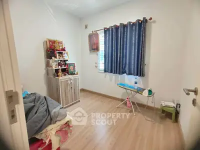 Cozy bedroom with wooden flooring, blue curtains, and a small cabinet, perfect for a peaceful retreat.