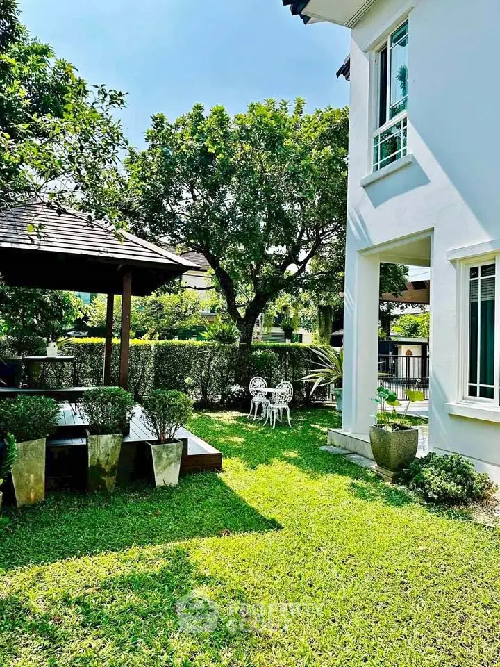 Charming garden view with lush greenery and elegant outdoor seating in a serene residential setting.