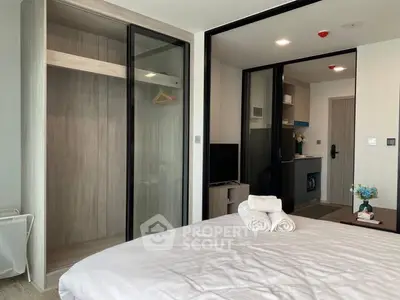 Modern bedroom with open closet and view into compact kitchen area