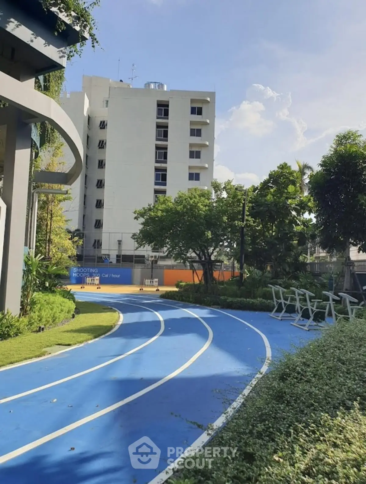 Modern apartment building with outdoor running track and lush greenery
