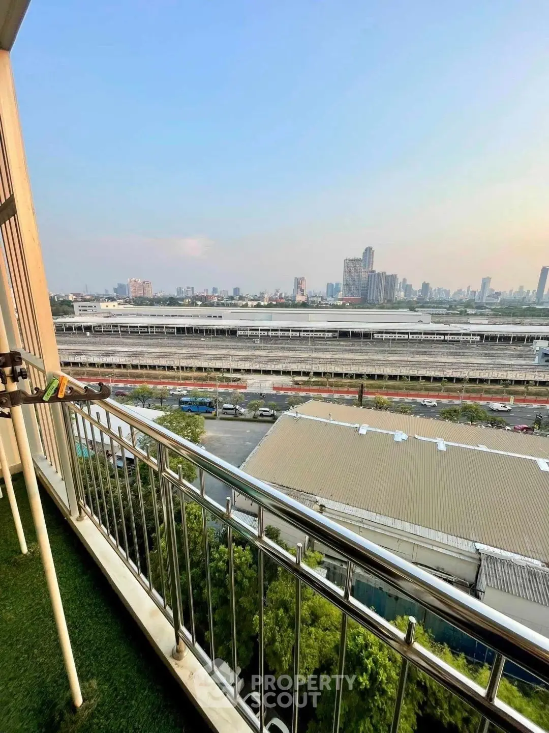 Stunning cityscape view from a high-rise balcony with lush greenery and urban skyline.