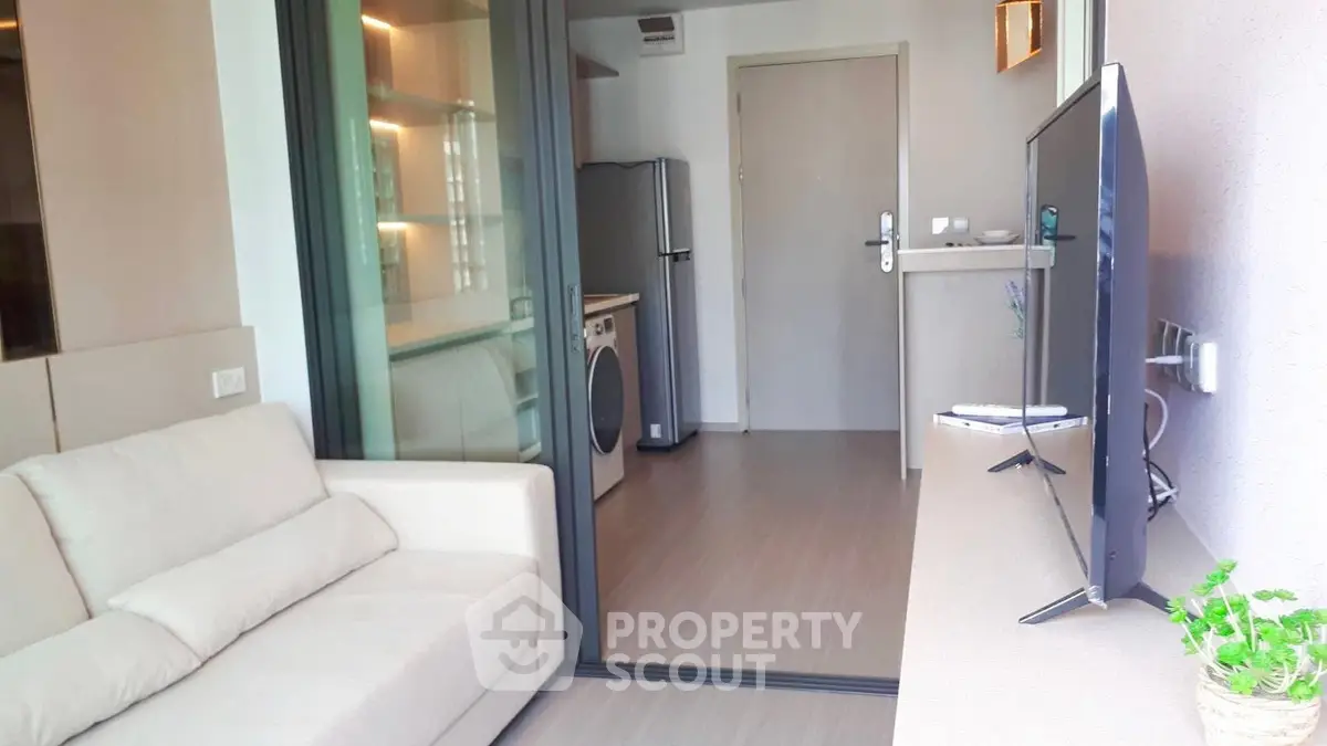 Modern apartment with open layout featuring living room and kitchen with washing machine.