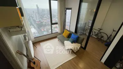 Modern living room with city view, cozy sofa, and wooden flooring in high-rise apartment.