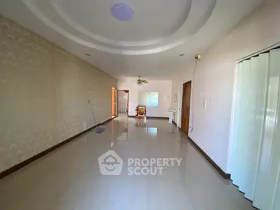 Spacious empty living room with glossy tiled floors and elegant ceiling design.