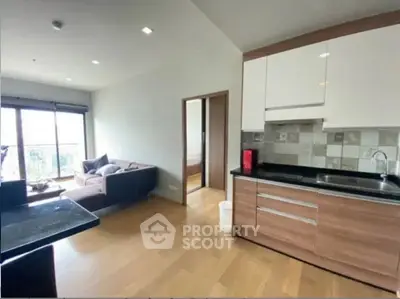 Modern open-layout kitchen and living room with wooden flooring and natural light.