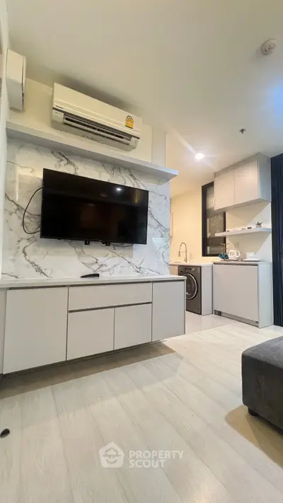 Modern living room with sleek TV setup and stylish kitchen area