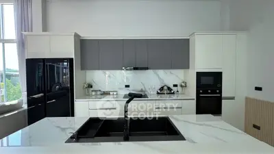 Modern kitchen with sleek black appliances and marble countertops, featuring an open layout and ample natural light.