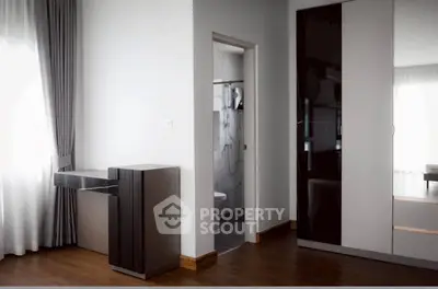 Modern bedroom with sleek wardrobe and elegant curtains, featuring a glimpse into a stylish bathroom.