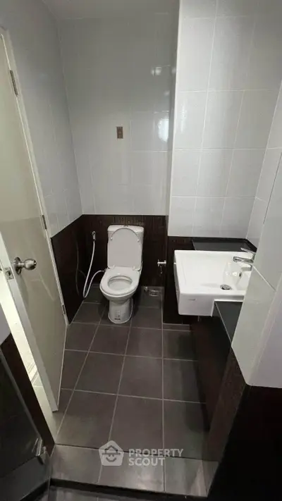Modern bathroom with sleek design and contemporary fixtures, featuring a toilet and sink.