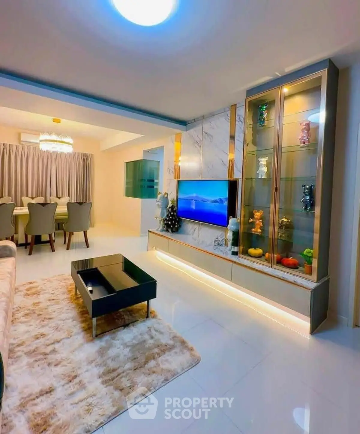 Luxurious living room with modern decor and elegant dining area, featuring a sleek TV unit and plush rug.