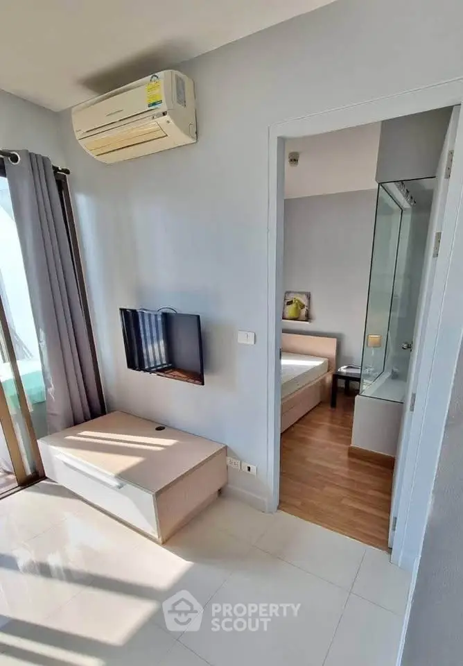 Modern apartment interior with air conditioning and TV, featuring a glimpse into a cozy bedroom.