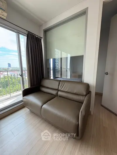 Modern living room with sleek sofa and large window offering stunning city view.