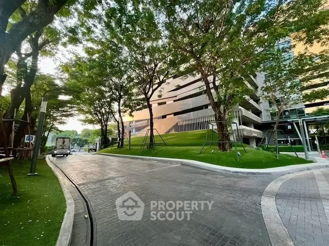 Modern building exterior with lush greenery and paved driveway, ideal for urban living.
