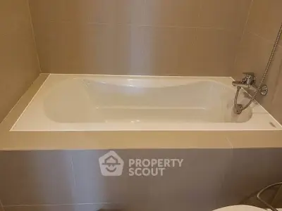 Modern bathroom with sleek bathtub and neutral tile design, perfect for relaxation and comfort.