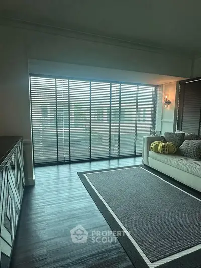Spacious living room with large windows and modern decor, perfect for relaxation and entertaining.