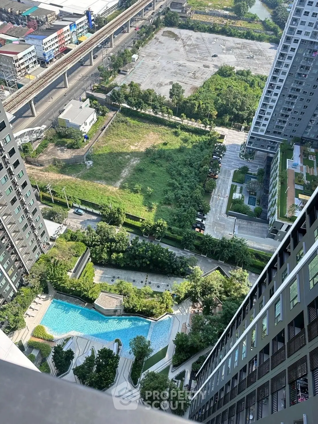 Stunning aerial view of modern high-rise buildings with lush greenery and a sparkling pool, perfect urban living.