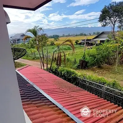 Serene countryside view from a spacious balcony, showcasing lush greenery and distant mountains, ideal for relaxation and nature lovers.