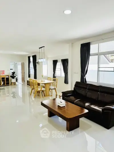 Spacious modern living room with dining area, featuring sleek furniture and natural light.