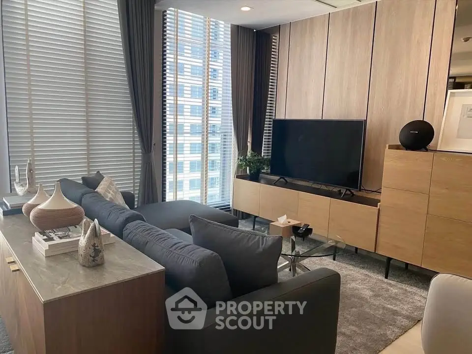 Modern living room with sleek furniture and large windows offering city views.