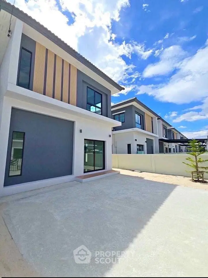 Modern two-story house with sleek design and spacious driveway under a clear blue sky.