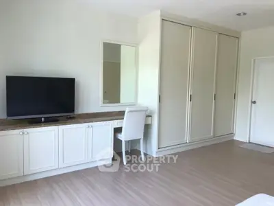 Spacious bedroom with built-in wardrobe and TV, perfect for modern living.