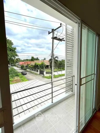 Charming balcony view with sliding glass doors overlooking a serene neighborhood street.